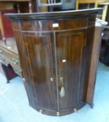 A GEORGE III INLAID MAHOGANY BOW FRONTED CORNER CUPBOARD WITH SPICE DRAWER