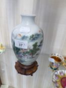 AN ORIENTAL PORCELAIN OVULAR VASE, PAINTED WITH A MOUNTAIN VILLAGE, 6 ½” HIGH, ON CARVED HARDWOOD