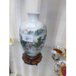 AN ORIENTAL PORCELAIN OVULAR VASE, PAINTED WITH A MOUNTAIN VILLAGE, 6 ½” HIGH, ON CARVED HARDWOOD