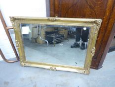 AN OBLONG BEVELLED EDGE WALL MIRROR, IN SWEPT GILT FRAME, 25” X 35” OVERALL