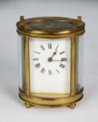 EARLY TWENTIETH CENTURY FRENCH OVAL BRASS PRESENTATION CARRIAGE CLOCK, with top handle, Roman mask