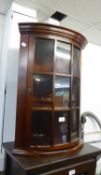 A MAHOGANY SMALL BOW FRONTED MURAL CORNER CUPBOARD WITH GLAZED DOORS