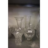 AN URN SHAPED CUT GLASS VASE ON SQUARE PLINTH BASE (AS FOUND); A CUT GLASS TRUMPET FLOWER VASE AND