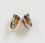 PAIR OF CLIP EARRINGS, each set with a cabochon oval transluscent golden amber