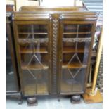 AN ART DECO OAK CARVED BOOKCASE HAVING TWO GLAZED DOORS ON BULBOUS FEET