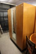 A 1960's G-PLAN TEAK AND CREAM WARDROBE, HAVING BI-FOLDING DOOR, SINGLE DOOR AND CENTRAL MIRROR (A.