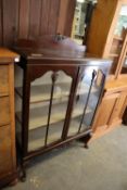 A GEORGE V MAHOGANY TWO DOOR DISPLAY CABINET, RAISED ON CABRIOLE LEGS