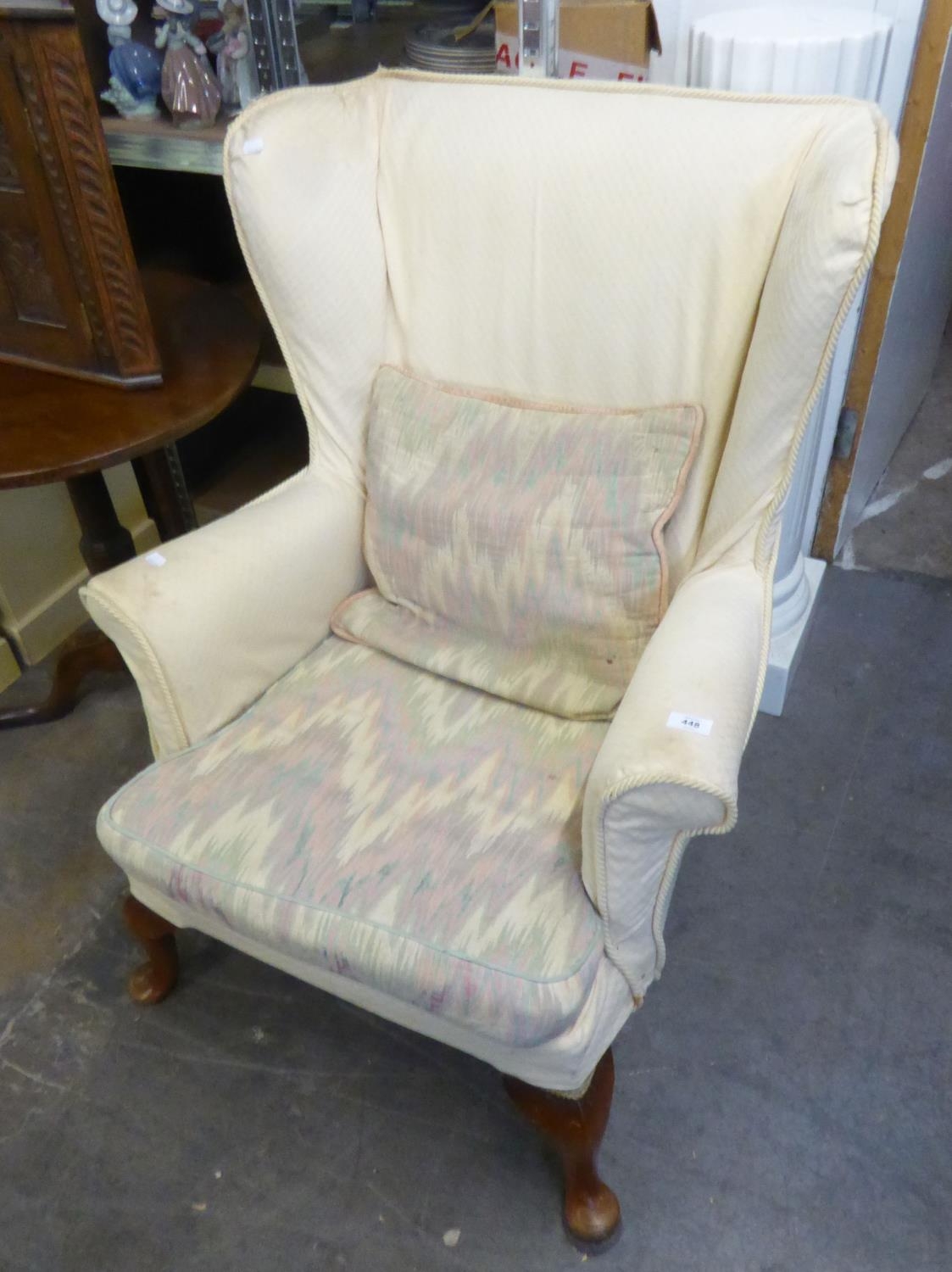 A WINGED FIRESIDE ARMCHAIR, WITH CREAM FABRIC LOOSE COVER, CABRIOLE FRONT SUPPORTS