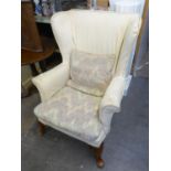 A WINGED FIRESIDE ARMCHAIR, WITH CREAM FABRIC LOOSE COVER, CABRIOLE FRONT SUPPORTS