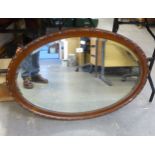 AN OVAL BEVELLED EDGE WALL MIRROR, IN A WALNUT CAVETTO FRAME