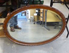 AN OVAL BEVELLED EDGE WALL MIRROR, IN A WALNUT CAVETTO FRAME
