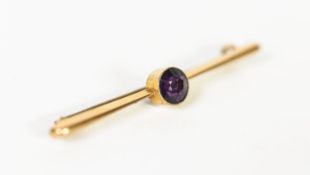 GOLD COLOURED METAL BAR BROOCH, collet set with a circular amethyst, 2gms (tests 9ct)