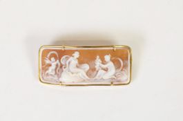CURVED OBLONG SHELL CAMEO BROOCH, well-carved wtih a winged cherub and two female figures in the