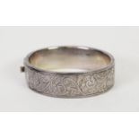 SILVER BROAD HINGE-OPENING HOLLOW BANGLE, with foliate scroll embossed top, Birmingham 1946