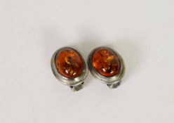 PAIR OF CLIP EARRINGS, each set with a cabochon oval transluscent golden amber