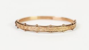 VICTORIAN GOLD COLOURED METAL HINGE OPENING HOLLOW BANGLE, the top half having chased and engraved