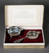 BOXED GEORGIAN STYLE SILVER TEA STRAINER AND STAND, with fancy scroll embossed handle and slender