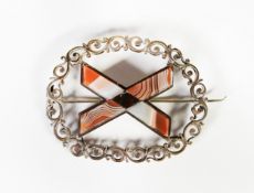 VICTORIAN LARGE OVAL BROOCH in the form of continuous silver scroll border framing a silver X
