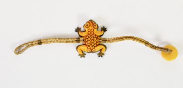 UNUSUAL ETHNIC TWO-STRAND CORD BRACELET, the top in the form of a carved butterscotch amber frog,