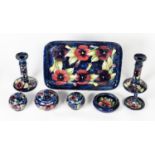 MOORCROFT PANSY PATTERN SEVEN PIECE TUBE LINED POTTERY DRESSING TABLE SET, on inky blue grounds,