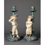 LATE NINETEENTH CENTURY PAIR OF ROYAL WORCESTER PORCELAIN FIGURAL CANDLESTICKS each painted in muted
