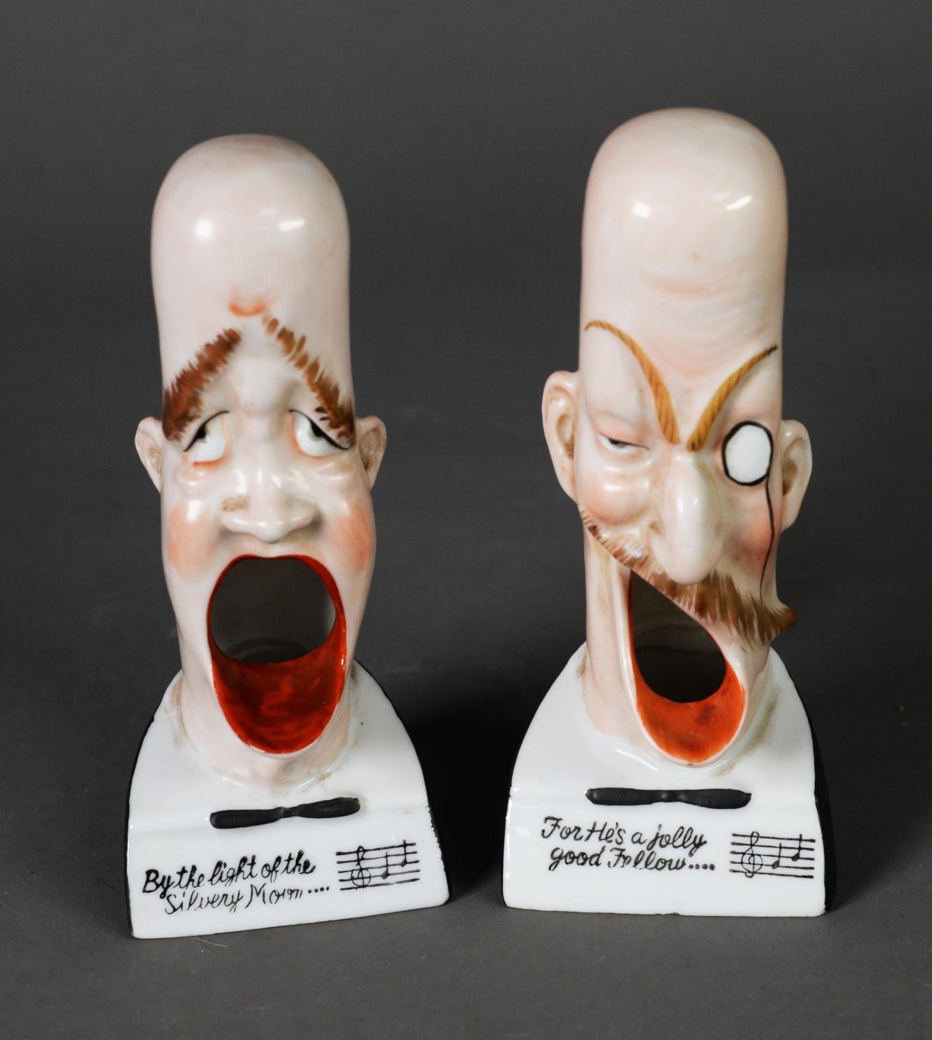 A PAIR OF PORCELAIN SMOKING HEAD ASHTRAYS, by Schafer & Vater; 'For he's a jolly good fellow' and '