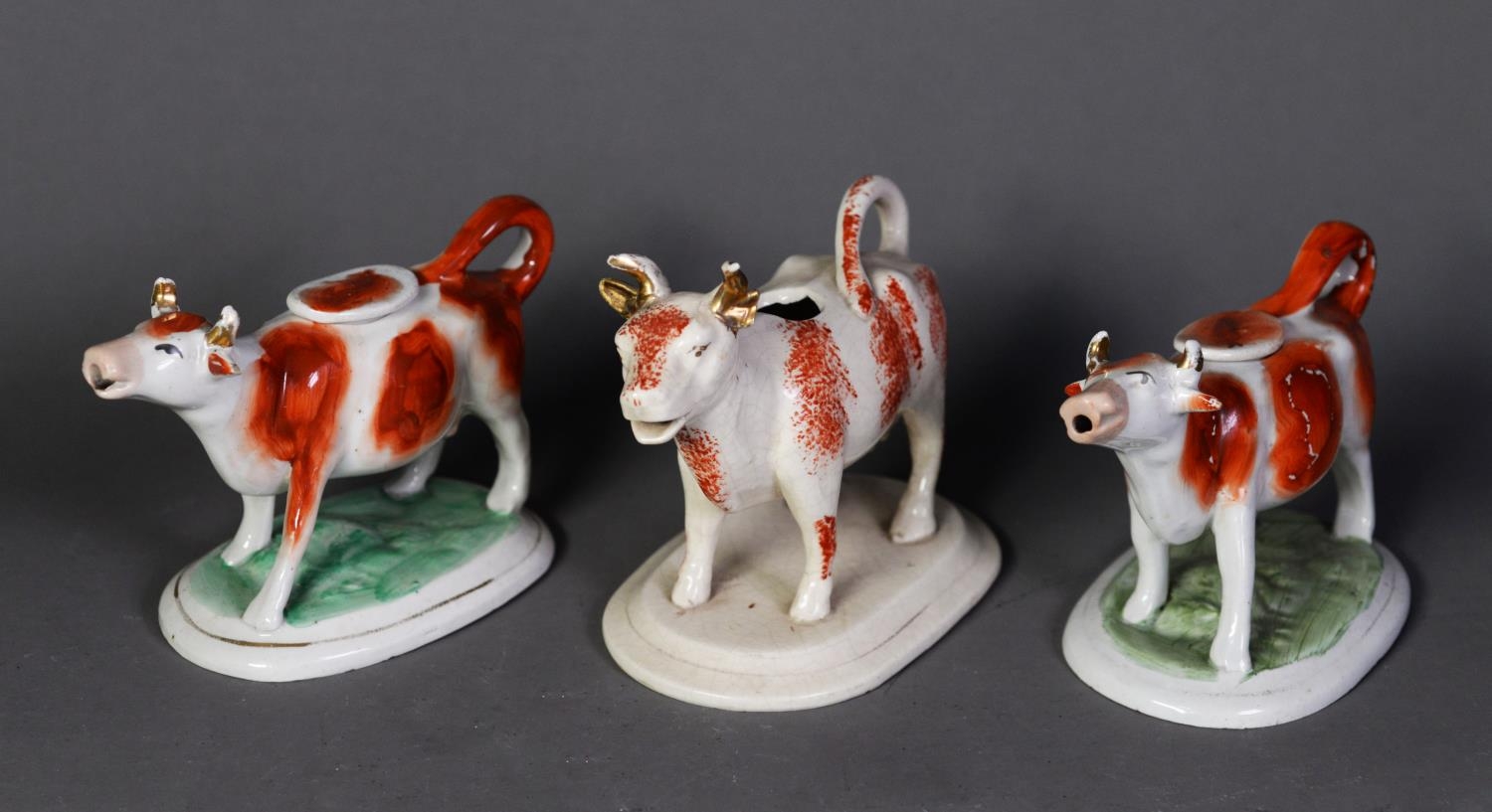 NINETEENTH CENTURY STAFFORDSHIRE POTTERY COW CREAMER, with burnt orange sponged coat, lacks cover,