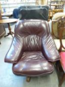 AN OAK AND LEATHER REVOLVING ARMCHAIR, RECENTLY RE-UPHOLSTERED IN BURGUNDY, HAVING OAK SIDE ARMS AND