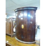 A SMALL MAHOGANY CORNER CABINET WITH AN OVAL INLAID DESIGN TO CURVED DOOR