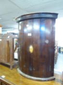 A SMALL MAHOGANY CORNER CABINET WITH AN OVAL INLAID DESIGN TO CURVED DOOR