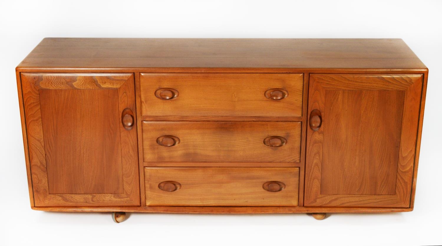 ERCOL LIGHT STAINED ELM SIDEBOARD, the oblong top above a central bank of three drawers, the top