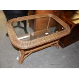 AN OVAL CANE COFFEE TABLE WITH GLASS INSET TOP AND CANE UNDERSHELF