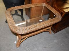 AN OVAL CANE COFFEE TABLE WITH GLASS INSET TOP AND CANE UNDERSHELF