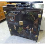 A CHINESE BLACK LACQUERED TWO DOOR CABINET, DECORATED WITH FIGURES AND BUILDINGS