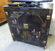 A CHINESE BLACK LACQUERED TWO DOOR CABINET, DECORATED WITH FIGURES AND BUILDINGS