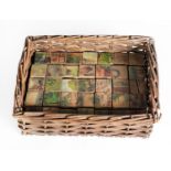 THIRTY FIVE EDWARDIAN SIX-SIDED WOODEN LITHOGRAPHED JIGSAW BLOCKS, contained in a covered wicker box