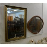 AN OBLONG WALL MIRROR IN EMBOSSED GILT FRAME AND AN OVAL SHAPED WALL MIRROR (2)