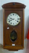 AN OAK WELLINGTON WALL CLOCK, WITH CIRCULAR WHITE ROMAN DIAL, LOZENGE SHAPED GLASS PANEL TO THE