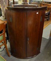 A MAHOGANY BOW FRONTED MURAL CORNER CUPBOARD, WITH TWO DOORS, THE INTERIOR WITH SMALL DRAWERS AND