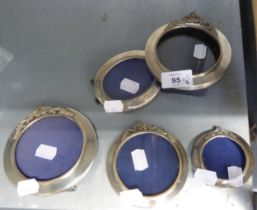FOUR SMALL CIRCULAR SILVER PICTURE FRAMES AND A SMALL OVAL SILVER PICTURE FRAME