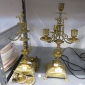 A PAIR OF BRASS THREE BRANCH CANDLE HOLDERS, RAISED ON PAW FEET (A.F.)