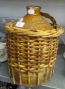 A BROWN STONEWARE JAR WITH WICKER HOLDER