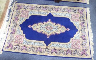 PAIR OF KIRMAN, PERSIAN RUGS each with a narrow lozenge shaped centre medallion, on a dark blue