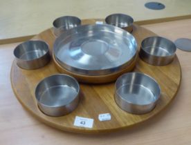 A STAINLESS STEEL LAZY SUSAN, WITH SIX SMALL BOWLS ROUND A CENTRE LARGE BOWL, ON TEAK REVOLVING BASE