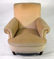 A HOWARD STYLE BOW FRONT ARMCHAIR covered in Beige fabric raised on turned front legs