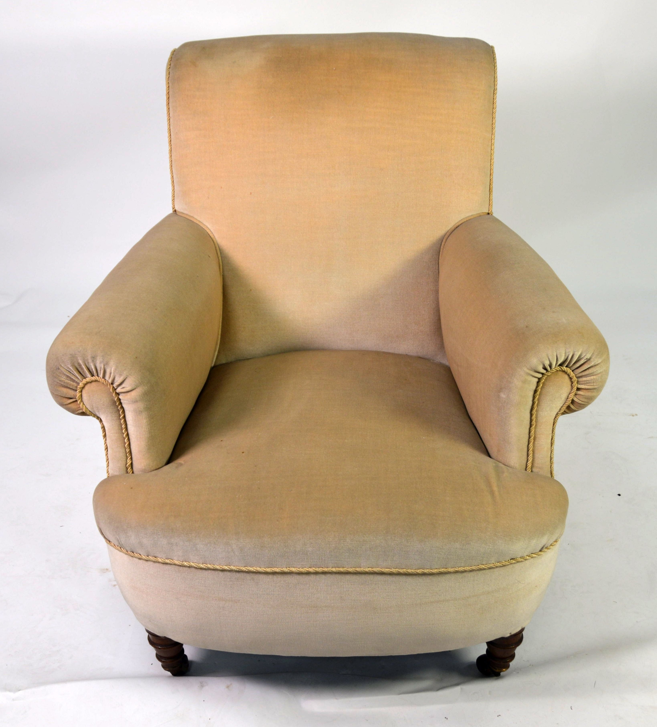 A HOWARD STYLE BOW FRONT ARMCHAIR covered in Beige fabric raised on turned front legs