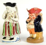 19th CENTURY STAFFORDSHIRE PEARL WARE FEMALE SNUFF-TAKER TOBY JUG, in standing pose, raised on a