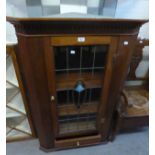 AN EDWARDIAN WALL-HUNG CORNER CABINET WITH LEADED GLASS DOOR AND UNDER DRAWER