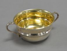 GEORGE V SILVER TWO HANDLED SUGAR BASIN, of girdled for with scroll handles and gilt interior, 2” (
