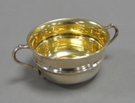 GEORGE V SILVER TWO HANDLED SUGAR BASIN, of girdled for with scroll handles and gilt interior, 2” (